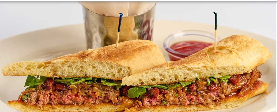 <p>Topped with Bacon, Caramelized Onion, Arugula, Housemade Steak Sauce and Garlic Aioli on a Toasted Roll</p>