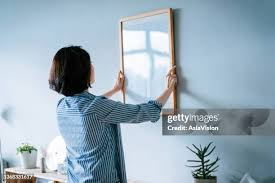 <p>The woman is hanging a picture.</p>