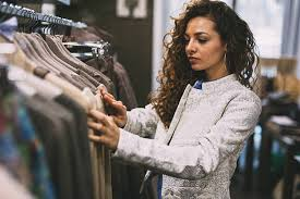 <p>The woman is looking through some clothes on a rack.</p>