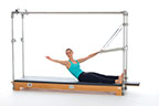 <p><strong>Setup</strong></p><ul><li><p>Setup: Starting in Sitting Forward position (page 111)</p></li><li><p>Resistance: medium <strong>[Top loaded] 2 springs</strong></p></li></ul><p><strong>Movement</strong></p><ul><li><p>Exhale: Round trunk, glide pelvis forward leaning back</p></li><li><p>Inhale: Release one hand, reach back, palm facing up</p></li><li><p>Exhale: Return hand to PTBar</p></li><li><p>Inhale: Straighten trunk, sit upright, return to start position</p></li></ul><p><strong>Muscle Focus</strong></p><ul><li><p>Spinal flexors</p></li><li><p>Spinal lateral flexors</p></li></ul><p><strong>Objectives</strong></p><ul><li><p>Spinal flexor control</p></li><li><p>Spinal lateral flexor stretch</p></li></ul><p><strong>Cues</strong></p><ul><li><p>Keep foot of stretching side pressing into pole</p></li><li><p>Keep reaching arm parallel to mat</p></li><li><p>Maintain pelvic lumbar stabilization</p></li><li><p>Allow neck to relax when looking back toward hand</p></li></ul><p></p>