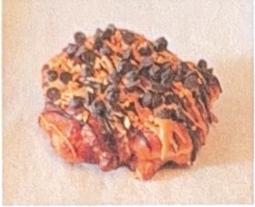 <p>Fried dough with banana chunks and cinnamon,</p><p>covered in glaze, finished with drizzled chocolate,</p><p>Peanut butter, chocolate chips and peanuts on top.</p>