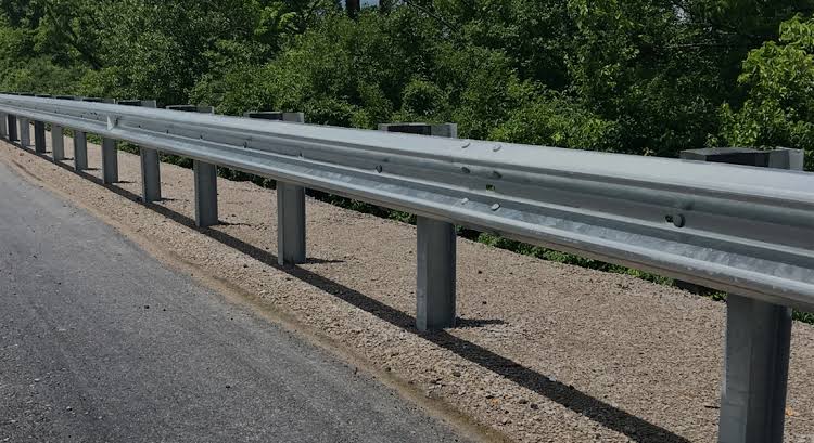 <p>A strong metal or concrete barrier installed along the edge of the road to prevent vehicles from leaving the roadway</p>