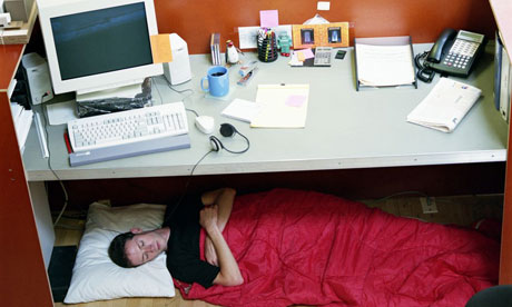 <p>The man is _____ the desk</p>
