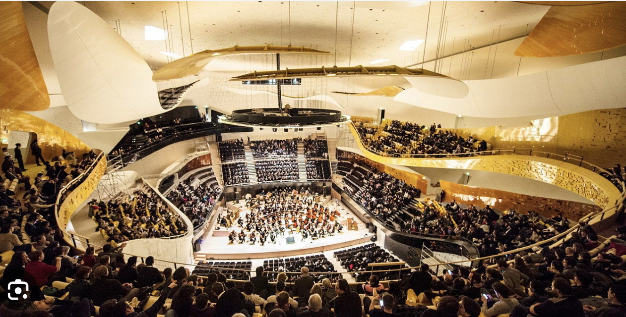 <p>Paris, Philharmonie, 2010-2015, arch. Jean Nouvel</p><ol><li><p><span><strong>Architectural Symbolism:</strong> The building functions as a new public landscape, designed as an accessible, upward-spiraling "hill" that connects the surrounding city to the Parc de la Villette with an exterior facade featuring an etched, multi-tonal bird motif.</span></p></li><li><p><span><strong>Acoustic Innovation:</strong> The auditorium features a revolutionary "surround" design, placing the audience close to the stage with floating balconies and cloud-shaped reflectors, optimizing sound clarity and intimacy.</span></p></li><li><p><span><strong>Urban Integration:</strong> Strategically located on the ring road, the venue is aimed at connecting central Paris with the diverse suburban communities to the north, offering a wide array of musical genres and educational programs.</span></p></li></ol><p></p>
