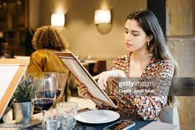 <p>The woman is making a selection from the menu.</p>