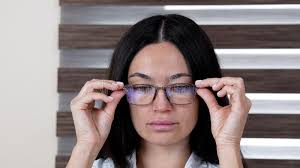 <p>The woman is putting on her glasses.</p>