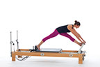 <p><strong>Setup</strong></p><ul><li><p>Standing on carriage, place one foot against shoulder rest (Up Stretch 1) other foot close to the front of carriage, kneel on carriage, place front foot on footbar, straighten back leg lifting knee of the carriage and pressing heel into shoulder rest, keep front knee over ankle</p></li><li><p>Resistance: light | <strong>Springs:&nbsp;1R</strong></p></li></ul><p><strong>Movement</strong></p><ul><li><p>Inhale: Stretch hip flexors of back leg (3-5 breaths)</p></li><li><p>Exhale: Straighten front leg, lower trunk forward (3- 5 breaths)</p></li><li><p>Inhale: Bend front leg, return to start position</p></li><li><p>Change sides after 2 repetitions</p></li></ul><p><strong>Muscle Focus</strong></p><ul><li><p>Hip flexors</p></li><li><p>Hip extensors</p></li></ul><p><strong>Objectives</strong></p><ul><li><p>Hip flexor stretch</p></li><li><p>Hip extensor stretch</p></li></ul><p><strong>Cues</strong></p><ul><li><p>Bias toward posterior tilt of pelvis during hip flexor stretch</p></li><li><p>Bias toward anterior tilt of pelvis during hamstring stretch</p></li><li><p>Move pelvis along horizontal line when straightening and bending front leg</p></li><li><p>Maintain spinal extensor engagement during hamstring stretch</p></li></ul><p></p>