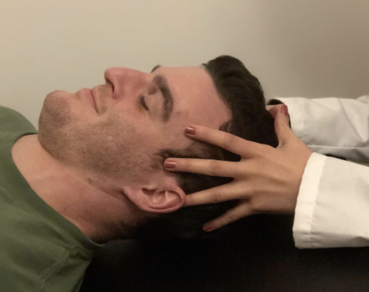 <p>Your forearms should be on table.</p><p></p><p><strong>Index fingers of each hand resting on the greater wings of the sphenoid bone (over the temples)</strong></p><p>Middle fingers placed on the zygomatic processes of the temporal bones</p><p>Ring fingers resting on the mastoid processes of the temporal bones (directly behind the ear)</p><p>Fifth (little) fingers placed on the squama of the occipital bone</p><p>Palms, if possible, resting on the parietal bones</p><p><strong>Thumbs resting against each other without contacting the patient’s skull</strong></p>