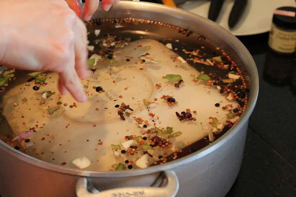 <p>Soaking food in a mixture of water, salt, and sometimes, sugar, herbs, and other seasonings to flavor, moisten, and tenderize it.</p>