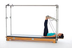 <p><strong>Setup</strong></p><ul><li><p>Lying supine, hips externally rotated, heels placed on outer edge of PTBar, toes under sides of PTBar, wide V position, legs bent</p></li><li><p>Resistance: medium to heavy <strong>[bottom loaded] 2 springs + safety belt</strong></p></li></ul><p><strong>Movement</strong></p><ul><li><p>Exhale: Straighten legs</p></li><li><p>Inhale: Bend legs, return to start position</p></li></ul><p><strong>Muscle Focus</strong></p><ul><li><p>Hip extensors</p></li><li><p>Knee extensors</p></li></ul><p><strong>Objectives</strong></p><ul><li><p>Hip extensor strength</p></li><li><p>Knee extensor control</p></li><li><p>Foot alignment and stabilization</p></li><li><p>Hip adductor control</p></li><li><p>Pelvic lumbar stabilization</p></li></ul><p><strong>Cues</strong></p><ul><li><p>Maintain hip extensor engagement</p></li><li><p>Reach heels toward ceiling when straightening legs</p></li><li><p>Maintain pelvic lumbar stabilization</p></li><li><p>Avoid excessive knee flexion (maximum of 90 degrees)</p></li><li><p>Straighten legs completely, avoiding hyperextension</p></li></ul><p></p>