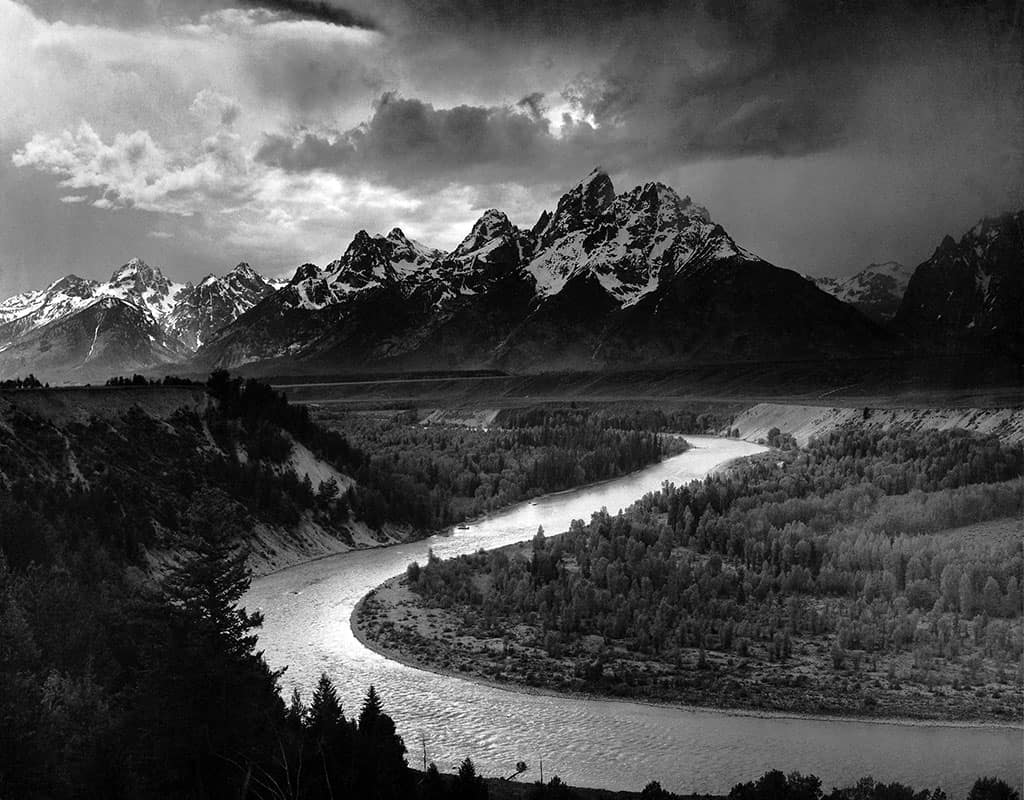 <p>Ansel Adams is defined by sharply detailed, high-contrast black-and-white landscapes, especially American national parks. His images are technically precise with dramatic lighting, deep blacks, and luminous whites. The “Zone System” aesthetic is key: controlled exposure, clarity, and majestic natural composition, often with grand, symmetrical scenery</p>