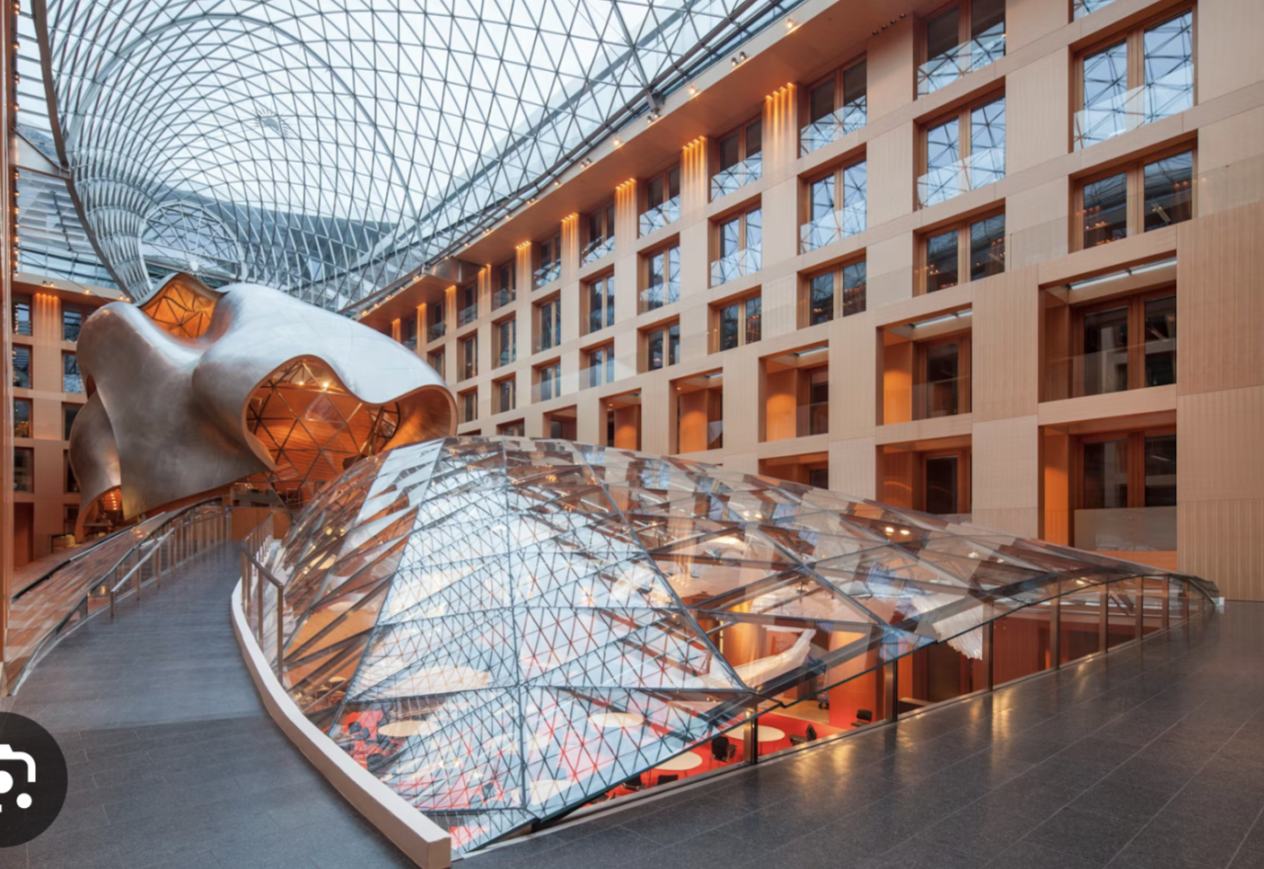 <p>Berlin, DZ Bank building: 1996-99, arch.: Frank Gehry</p><ol><li><p><span>Contextual Exterior/Surprising Interior: The facade, clad in yellow Italian limestone, respects the strict, historic aesthetic of Pariser Platz, intentionally masking a complex, curvaceous, and highly sculpted interior world.</span></p></li><li><p><span>The Sculptural Conference Hall: The heart of the atrium features a striking meeting hall that resembles a fish or submarine, utilizing stainless steel and timber to create a dramatic, organic, and floating volume inside a glass-vaulted space.</span></p></li><li><p><span>Symbolic Urban Location: Located directly next to the US Embassy, this building signifies the post-reunification revitalization of Berlin's center and represents DZ Bank's, formerly "Preussische Central-Genossenschaftskasse," return to its historic roots.</span></p></li></ol><p></p>