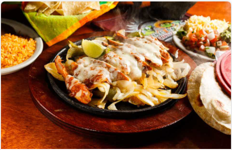 <p>Beef of chicken fajitas on a bed of grilled onions. Topped with a special chipotle sauce and Monterey Jack cheese. Served with guacamole, pico de gallo, and grated cheese.</p>