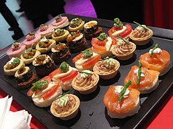 <p>• Named “sofa” because the garnish sits on top of the bread as people do on a sofa.</p><p>• A canapé is a type of starter/appetizer, <span>a small, decorative appetizer served on a </span>piece of bread (sometimes toasted) or cracker, wrapped or topped with some savory food.</p><p>• Often eaten in 1-2 bites, and may also be referred to as finger food, although not all finger foods are canapés.</p>