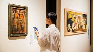 <p>He is viewing some artworks.</p>