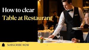 <p>The server is clearing dishes off the table.</p>