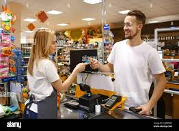 <p>The man is paying for his purchase.</p>