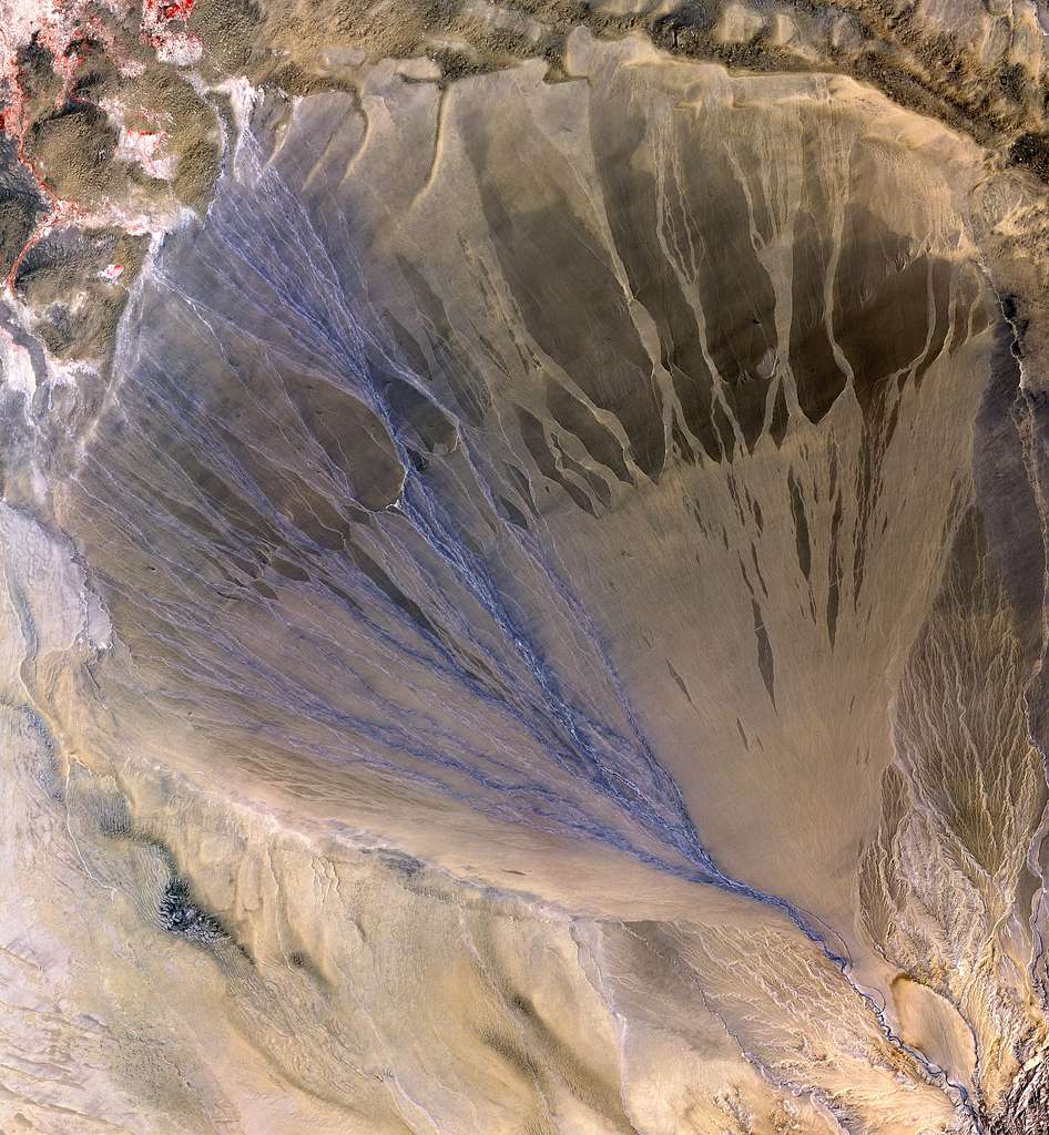 <p>water flowing through canyon and the debris that is collecting being deposited at the mouth of the canyon forming a cone shape </p>