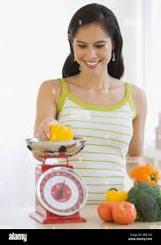 <p>The woman is weighing some vegetables.</p>
