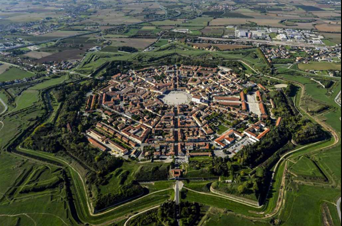 <p>Originally planned for defense, it was a circular/star shaped bastion designed against cannons. Still a grid-like pattern, but circular instead of square. It was made as an ideal city, but as no one wanted to live there due to the design, they had to pay convicts to live there. </p>
