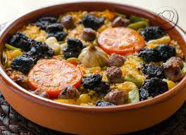 <p>Un plato que tiene salchichas, tomates, y ajo. En Valencia. </p>