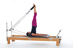 <p><strong>Setup</strong></p><ul><li><p>Lying supine in neutral spine position, hips externally rotated, legs straight on diagonal line (45 to 60 degrees), feet in straps, plantarflexed, headrest down</p></li><li><p>Resistance: light to medium | <strong>Springs: 1R +1B</strong></p></li></ul><p><strong>Movement</strong></p><ul><li><p>Inhale: Lift legs perpendicular to floor</p></li><li><p>Exhale: Roll up onto shoulder girdle</p></li><li><p>Inhale: Open legs shoulder width apart</p></li><li><p>Exhale: Roll down to sacrum, lower and close legs, return to start position</p></li></ul><p><strong>Muscle Focus</strong></p><ul><li><p>Spinal flexors</p></li><li><p>Hip extensors</p></li><li><p>Spinal extensors</p></li></ul><p><strong>Objectives</strong></p><ul><li><p>Spinal articulation</p></li><li><p>Hip extensor control</p></li></ul><p><strong>Cues</strong></p><ul><li><p>Use hamstrings concentrically rolling up, eccentrically rolling down</p></li><li><p>Anchor pelvis prior to roll up and following roll down</p></li><li><p>Keep carriage still during roll up and roll down</p></li></ul><p></p>