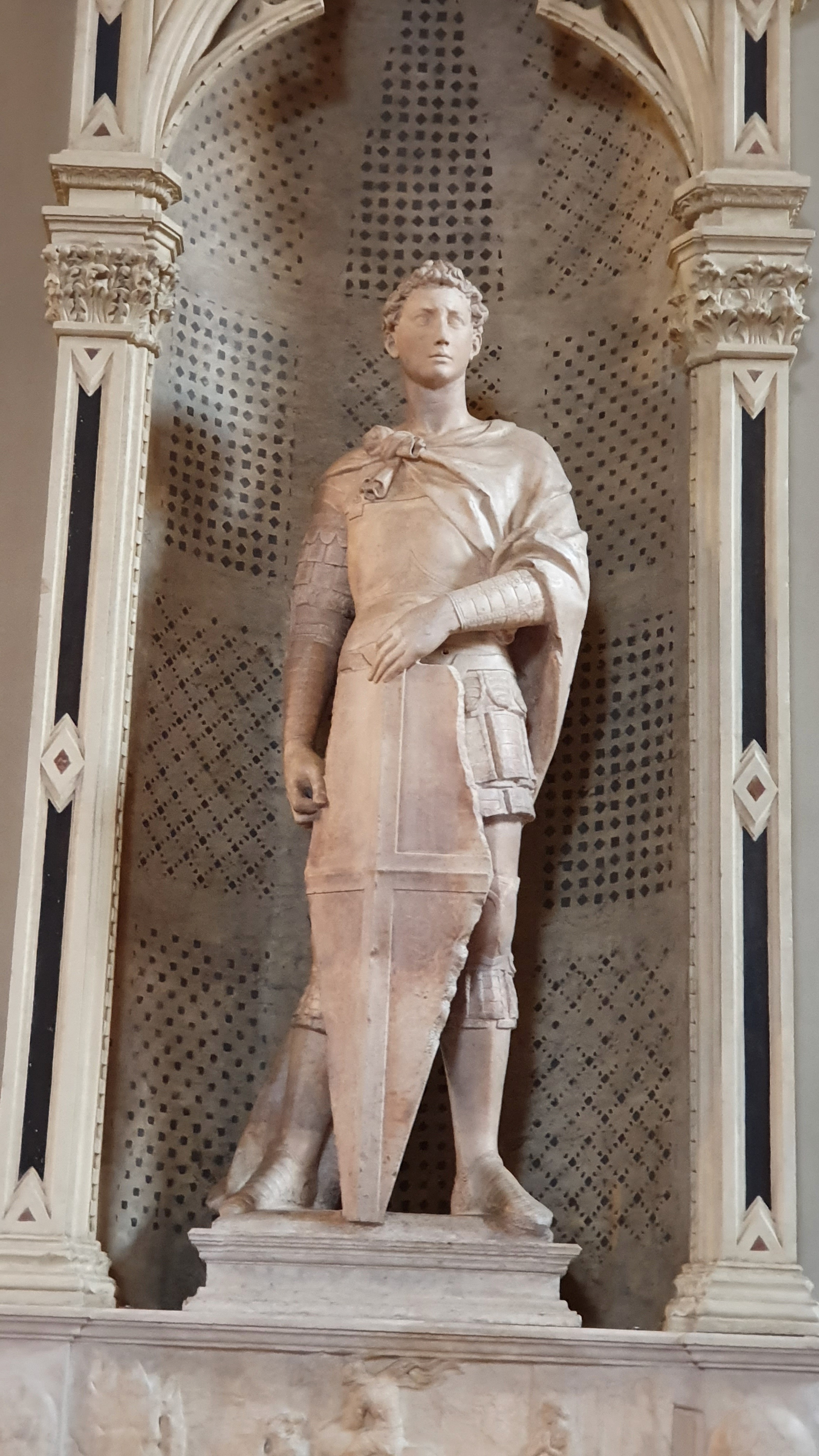 <p>Artist:<br>Title:<br>Period/movement:<br>Format:<br>Material/medium:<br><br><strong>Human problem/function:</strong> Installed for the Armorers and Swordmakers' Guild, the saint linked professional identity with courage, protection, and civic responsibility.</p><p><strong>Zone 2 — See and decode it</strong></p><p class="code-line"><strong>Recognition clues:</strong></p><ol><li><p>Young armored saint</p></li><li><p>Broad shield</p></li><li><p>Alert head and planted stance</p></li><li><p>Restrained readiness rather than active combat <strong>Visible evidence:</strong> Weight shift and focused gaze imply a thinking individual responding to danger.<br><strong>Psychology/attention:</strong> A stable base paired with a searching gaze creates readiness without panic—the bodily profile of controlled threat monitoring.</p></li></ol><p><strong>Zone 3 — Connect and explain it</strong></p><p class="code-line">Commissioned for a guild context, Saint George converts a Christian warrior into an image of disciplined civic agency. Donatello makes virtue appear as readiness, self-command, and rational attention. <strong>Portable insight:</strong> Competence often looks like calibrated readiness: enough tension to act, but enough control to keep perception and judgment available.</p><p><strong>Zone 4 — Study references</strong></p><p class="code-line"><strong>Note-taking guide:</strong> The Chapter 21 guide links guild patronage with civic virtue. The planted stance and alert gaze communicate disciplined readiness rather than uncontrolled aggression.<br><strong>Worksheet:</strong> Chapter 21, Question 8: the real helmet and sword represented and advertised the Armorers and Swordmakers’ Guild.</p>