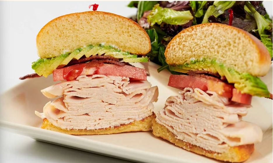 <p>Freshly Roasted Turkey Breast, Smoked Bacon, Avocado, Tomato and Mayonnaise on a Toasted Bun. Served with a Green Salad</p>