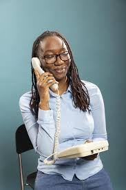 <p>The woman is holding a receiver to her ear.</p>