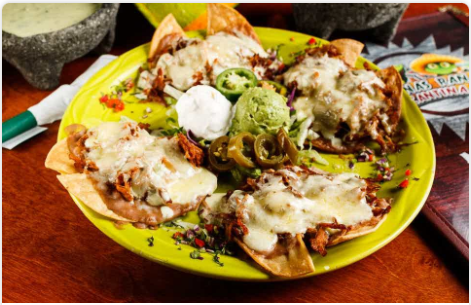<p>Slow-roasted, seasoned pork carnitas topped with sour cream sauce, refried beans, Monterey cheese, guacamole, sour cream, and jalapenos.</p>